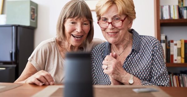 Two older women check out an Alexa assistant device.